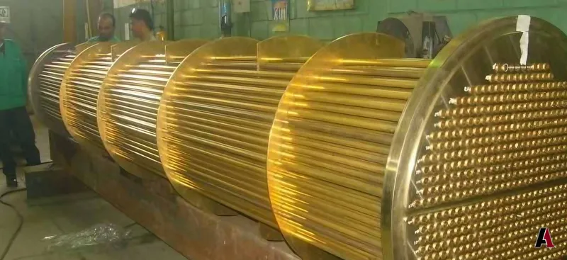 Shell-and-tube heat exchanger bundle with brass tubes and baffle plates in a fabrication shop, designed by A1 Design and Construction