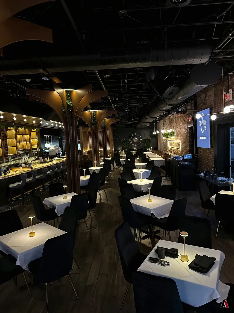 Dining room of The Clock restaurant and lounge with arched wood columns, a backlit bar, white tablecloths and gold table lamps, designed by A1 Design and Construction